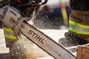 A firefighter cutting plywood with a saw