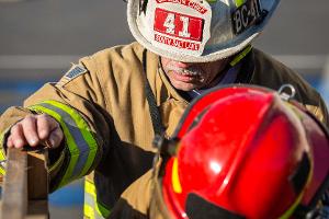 Two firefighters climbing over a wooden obstacle