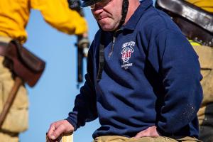 A firefighting instructor supervising sitting on a metal wall