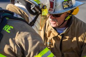 Two firefighters headbutting their helmets together