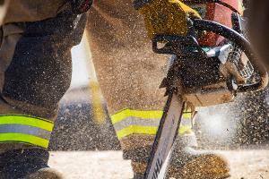 A firefighter cutting plywood with a saw