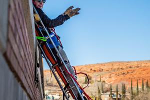 A person repelling from a building in a gurney type harness