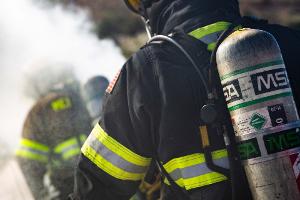 Firefighter spraying fire extinguisher on another firefighter