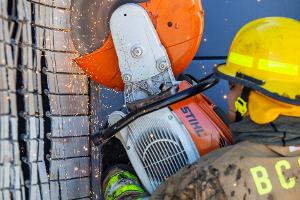 A firefighter cutting a brick wall with a saw