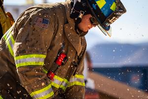 A firefighter cutting plywood with a saw