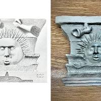 Plaster cast of a sun with a face and trumpets above it