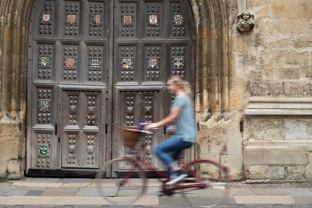 Female student rides past the Bodleian Library's Great Gate.