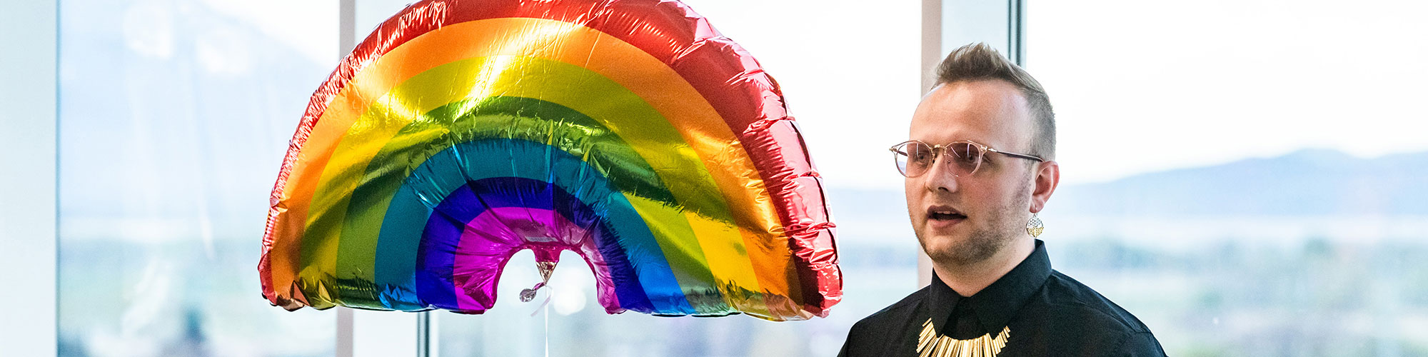 A person standing next to a rainbow balloon