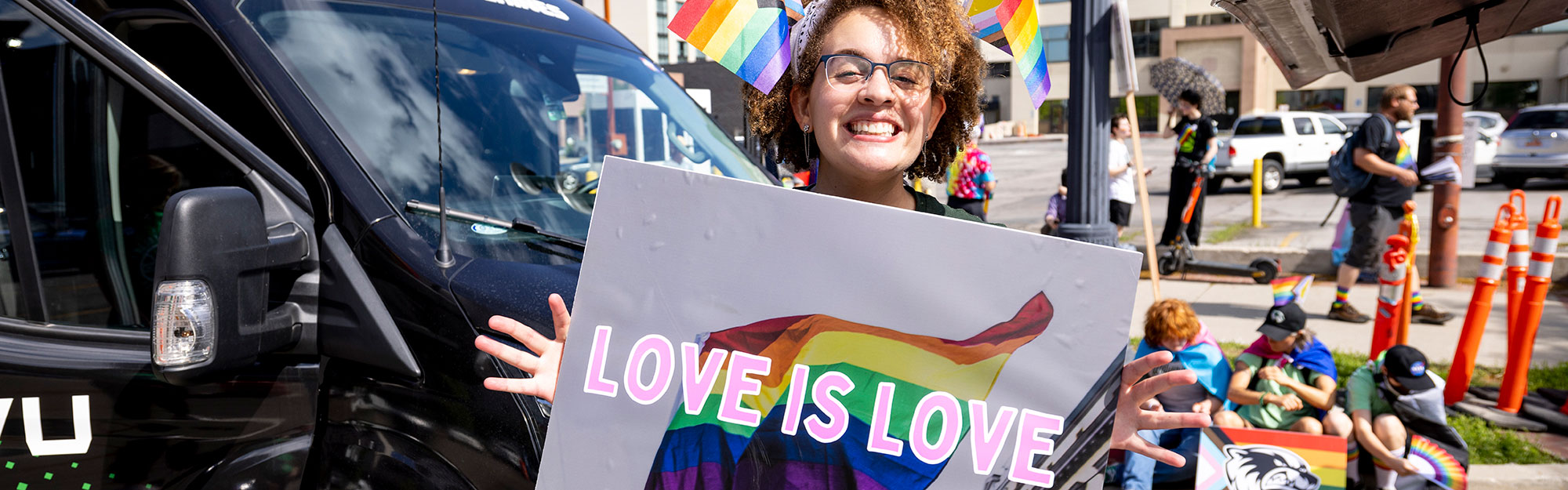 A woman holding a sign that says love is love, smiling at the camera.