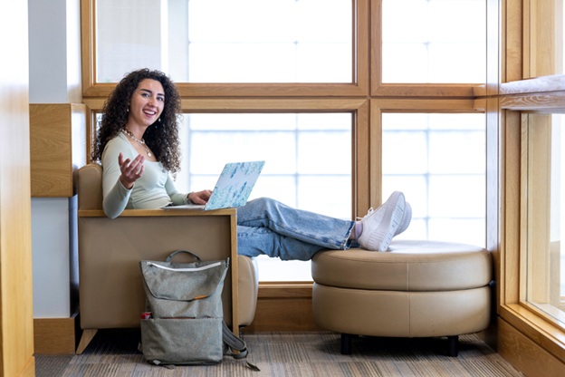 Woman studying in the library, smiling at the viewer.