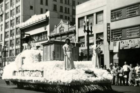 Historical, black and white image of a royalty float in a parade.