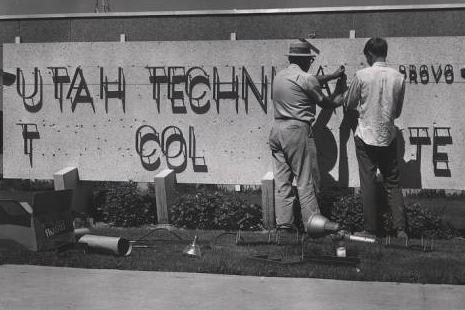 UVU Historical Photo 2 men putting up a large utc sign