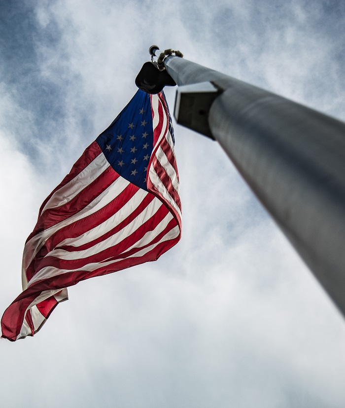 a picture of the american flag hanging on a flag pole from below