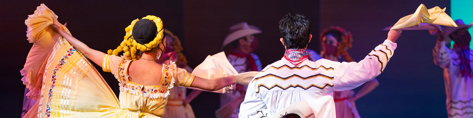 Traditional Latino dancers, a woman with her skirt held high to the left and a man with his had held up to the right.