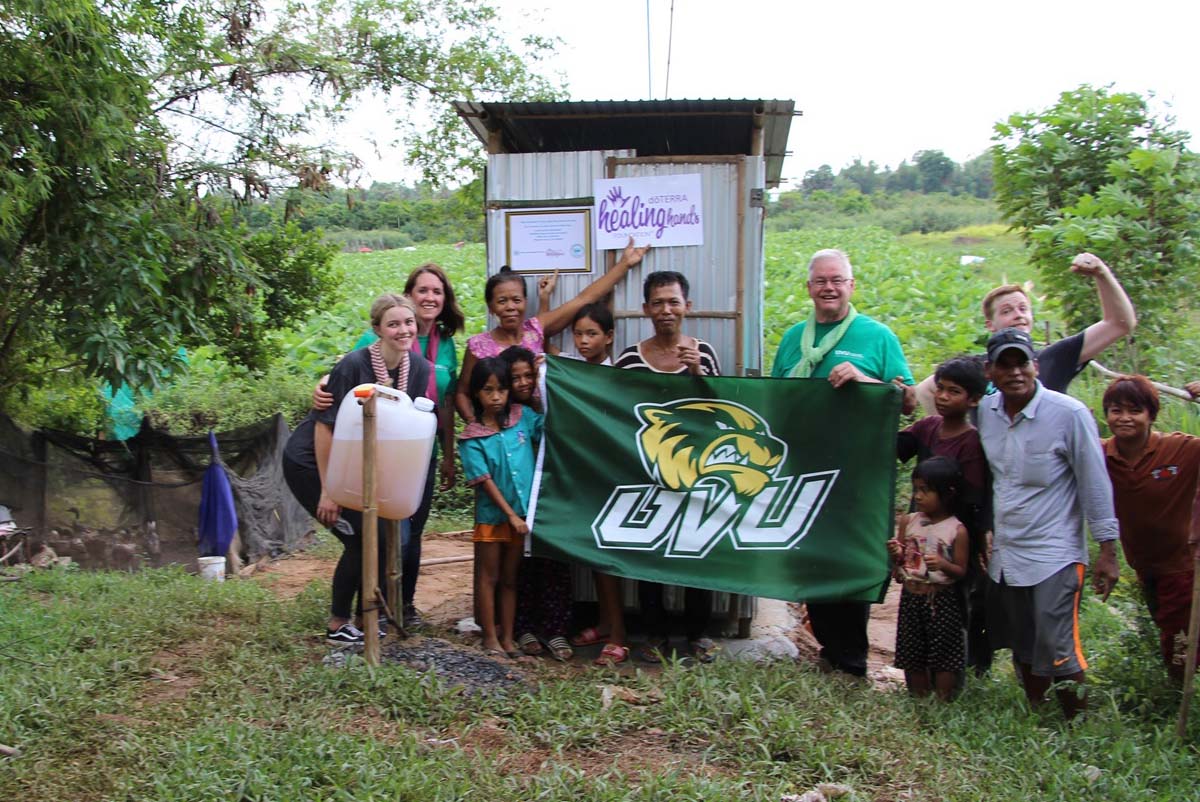 Professor Barthel and team pose with UVU flag in front of a new latrine. 