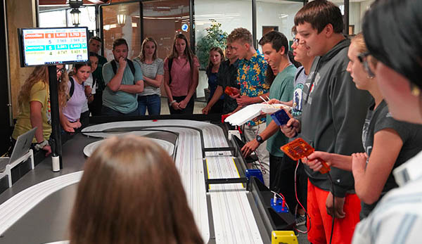 High school students take a break and race on a miniturate remote control car track.