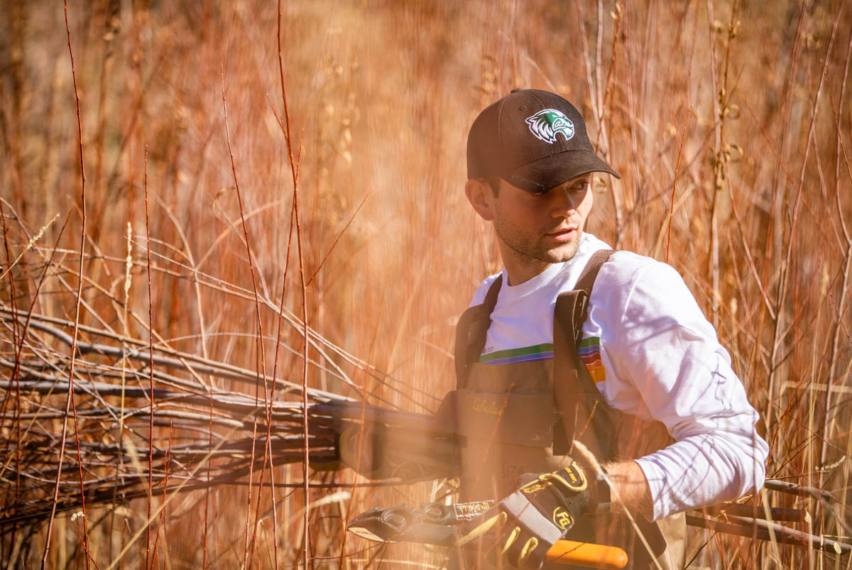 A Utah Valley University student wearing a wolverine hat and volunteering during alternative break.