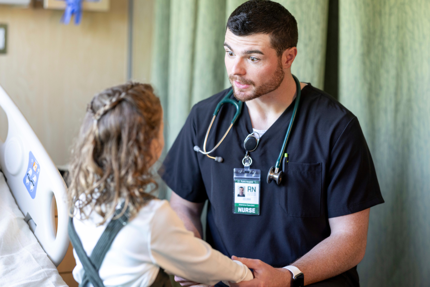 A male nurse comforts a young patient.