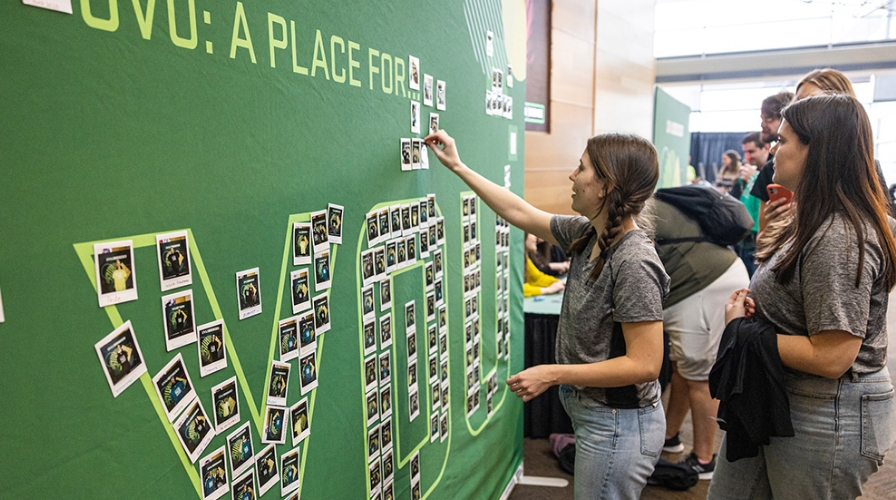 Group of students placing Polaroid pictures on a "UVU" sign.