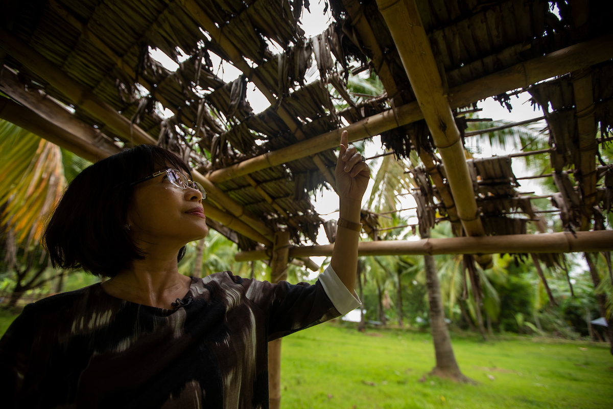 President Tuminez points to holes in a nipa-grass hut.