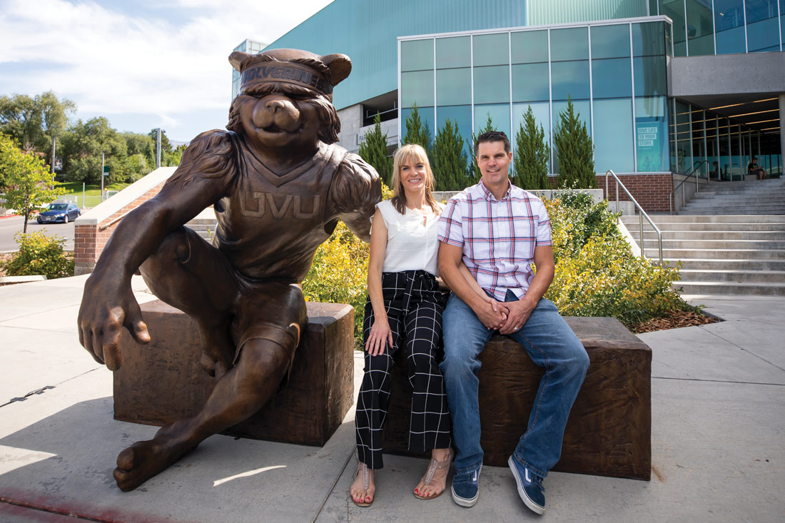 Virgil Oertle and his wife sit next to his statue outside the Student Life and Wellness Center.