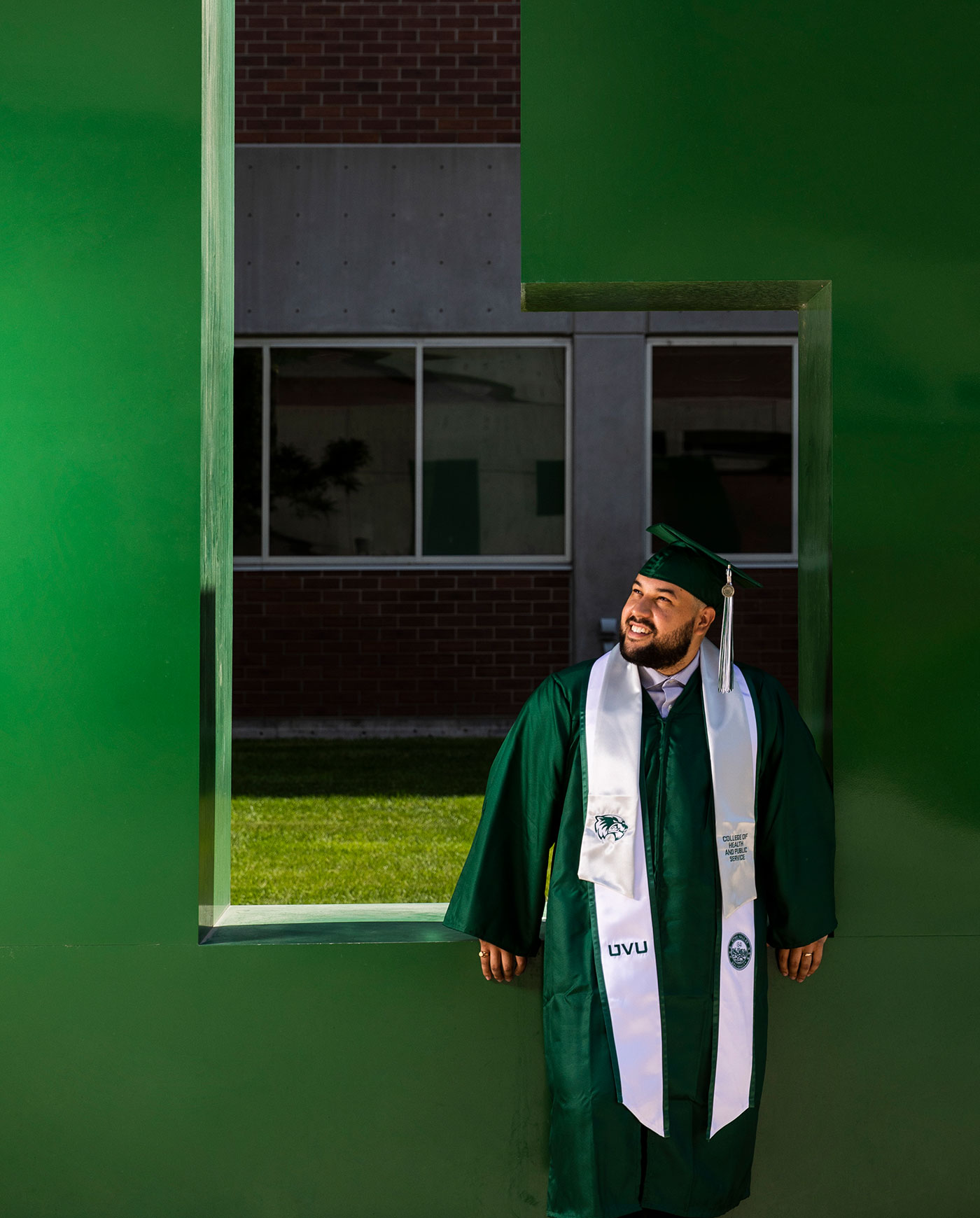 Graduate next to giant UVU letters
