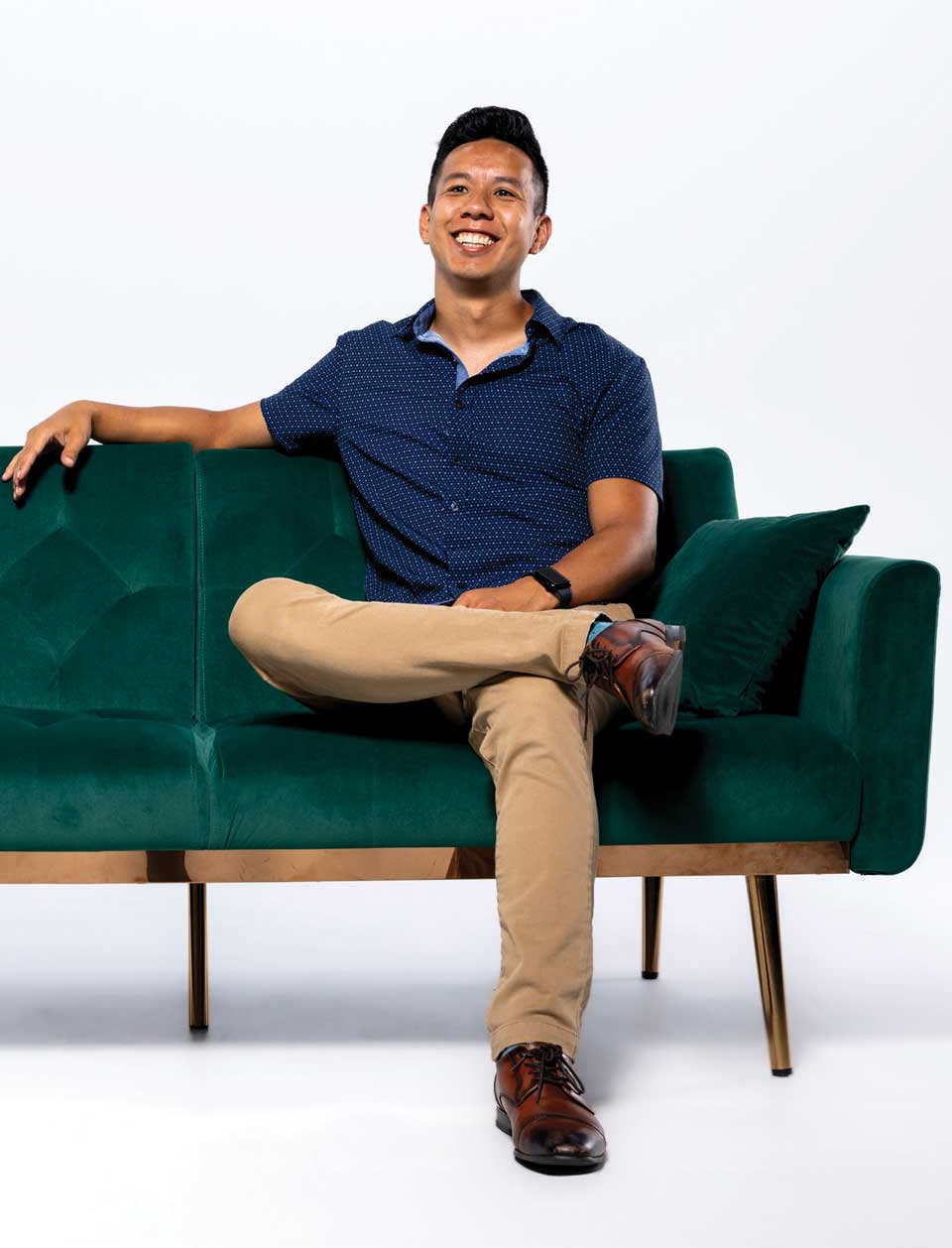 William Ng casually sits on a green couch.