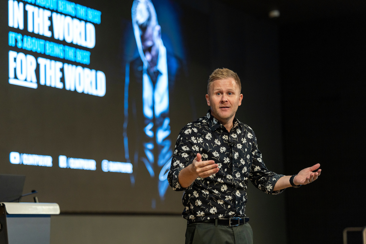 Clint Pulver speaking animatedly on stage during his Halladay Lecture Series presentation.