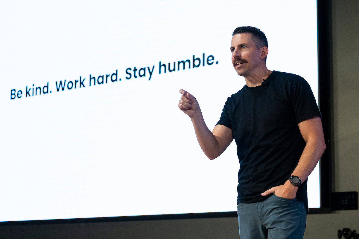 Taylor Napierski speaks to UVU students with a slide behind him that reads “Be kind. Work hard. Stay humble.”