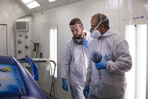 Two men dressed in personal protective equipment with breathing aparratuses