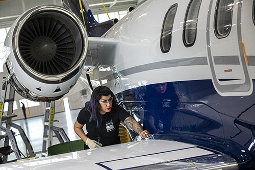 A female student cleaning an airplane wing