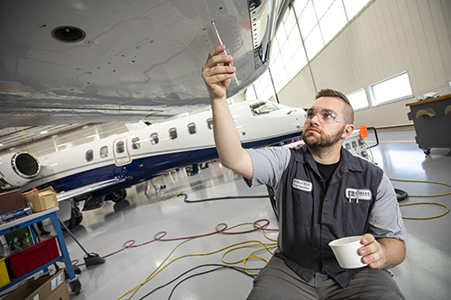 A man holding a test tub up to an airplane