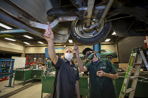 Two people looking at the under carraige of a car