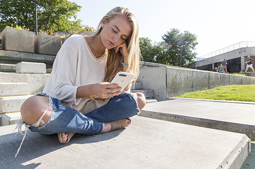 A woman sitting on the ground looking at her phone