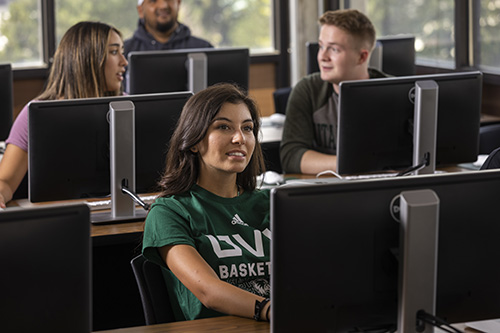 Students behind individual computers sitting in a class