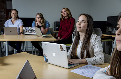 A student sitting in a classroom with a laptop on their desk