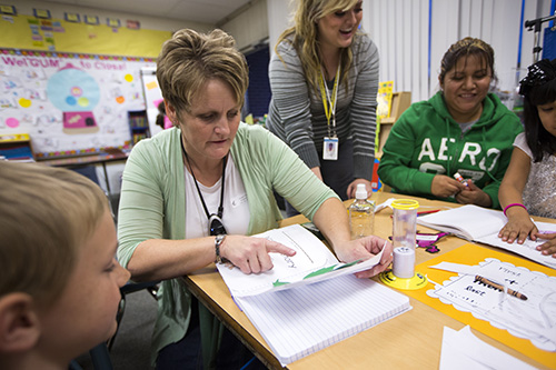 Two teachers helping students with work