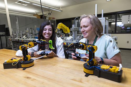 Two Engineering students use robotic arms.