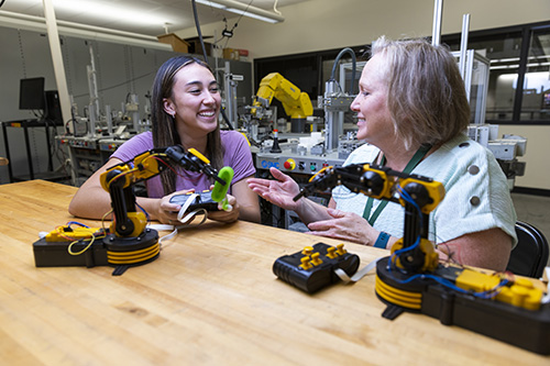 Two Engineering students use robotic arms.