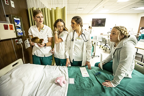 Four female nurses standing around a hospital bed