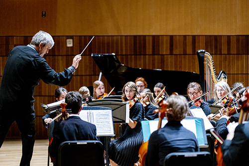 Conductor conducts orchestra in the Noorda.