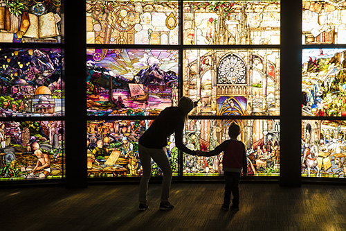 Silhouette of two people enjoy the stained glass windows.