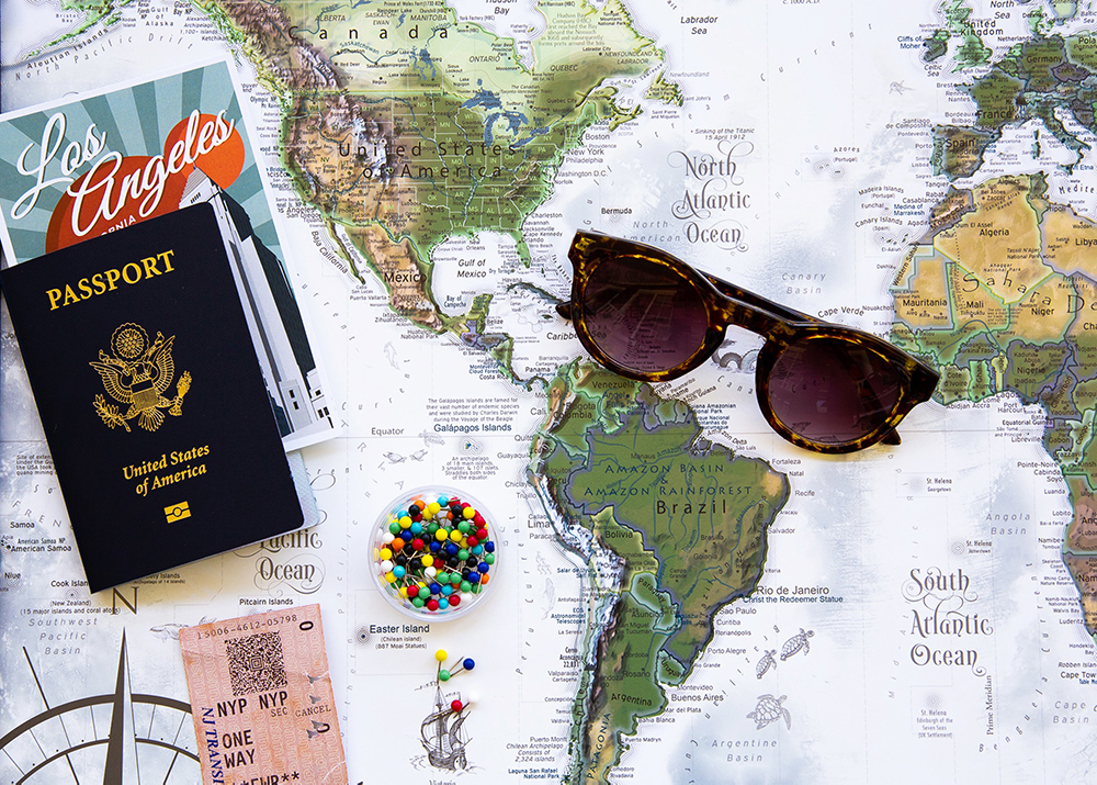 Artsy photo of a map, sunglasses, and passport.