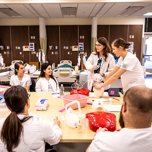 Nursing students simulating treatment with manikins in simulation room