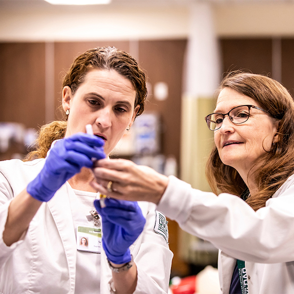 Instructor teaching student how to read a syringe