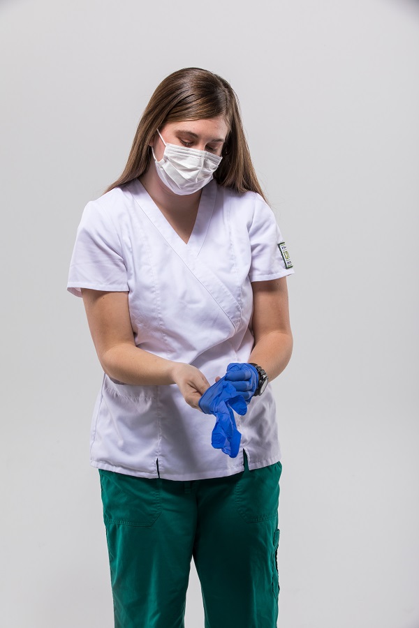 A woman puts on gloves in a nurse uniform