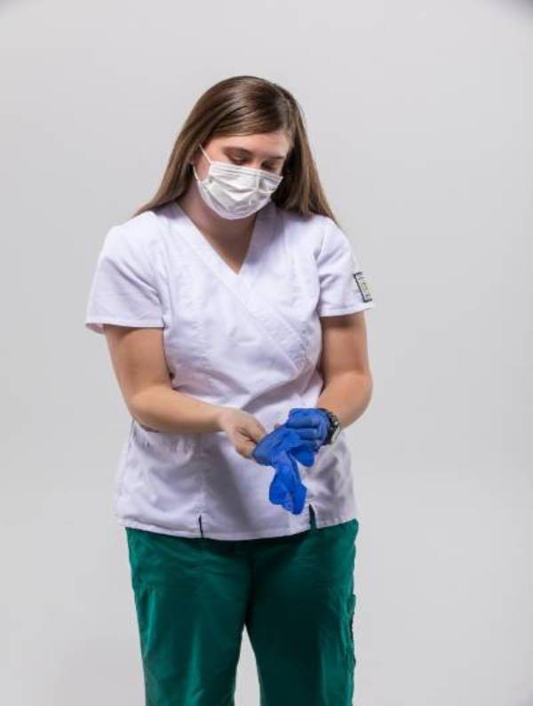 A woman puts on gloves in a nurse uniform