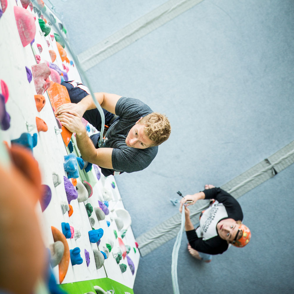 a person belaying another person climbing the indoor wall