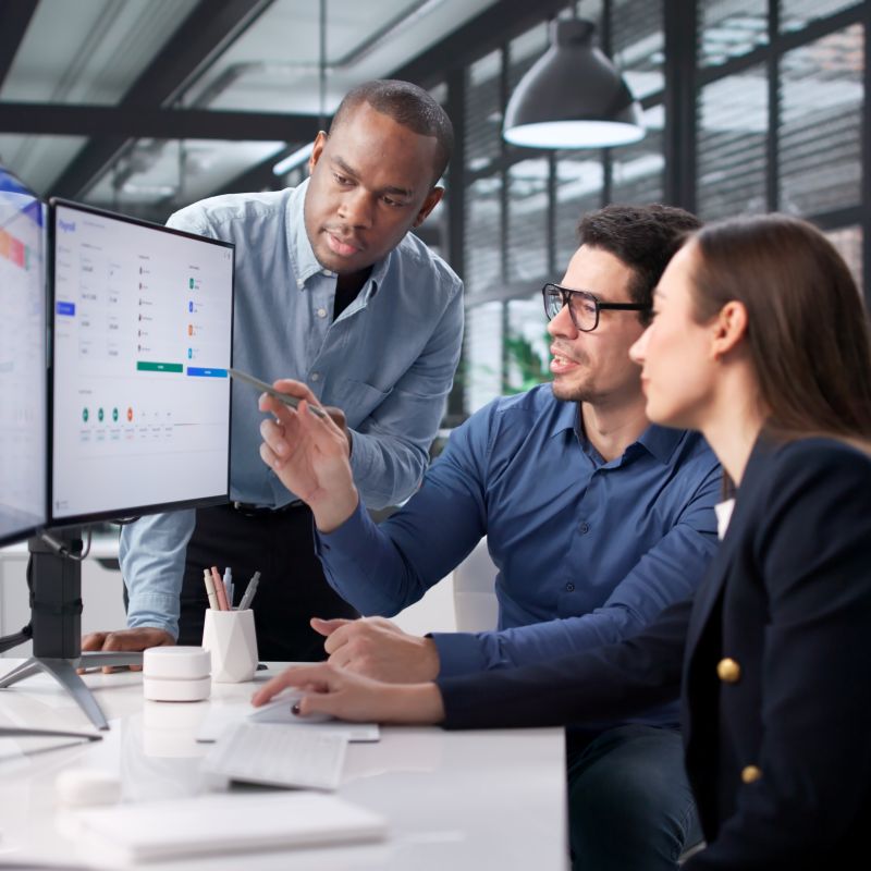 employee showing coworkers a spreadsheet on their monitor screen