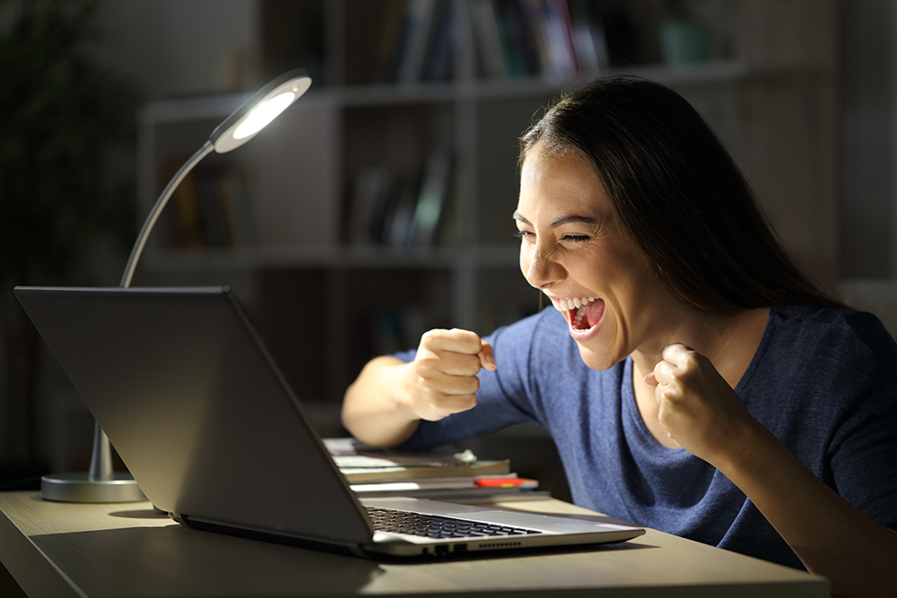Woman looking at laptop with an excited expression